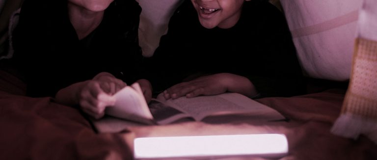 Niños leyendo en la cama historias de terror, recomendaciones de cuentos y libros este Halloween