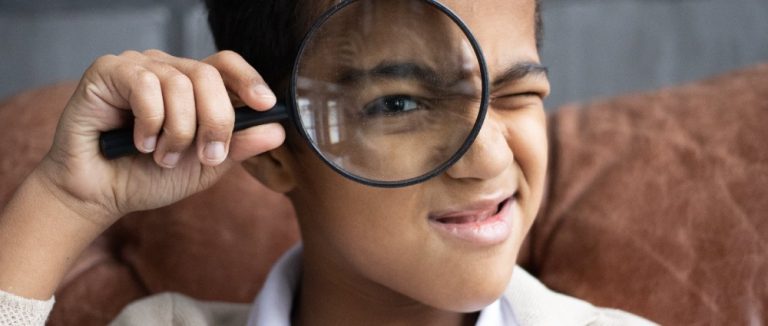 Niño con lupa para ilustrar las recomendaciones de series libros infantiles de investigación.